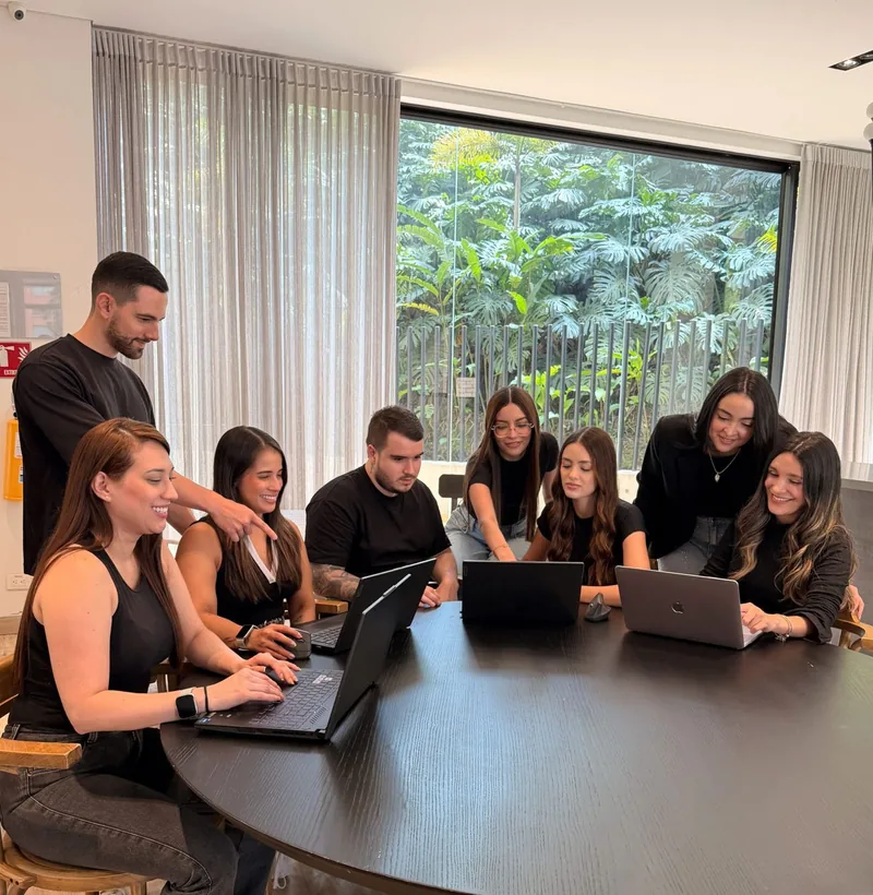 El equipo de Mento trabajando alrededor de una mesa con portátiles, frente a un ventanal con plantas